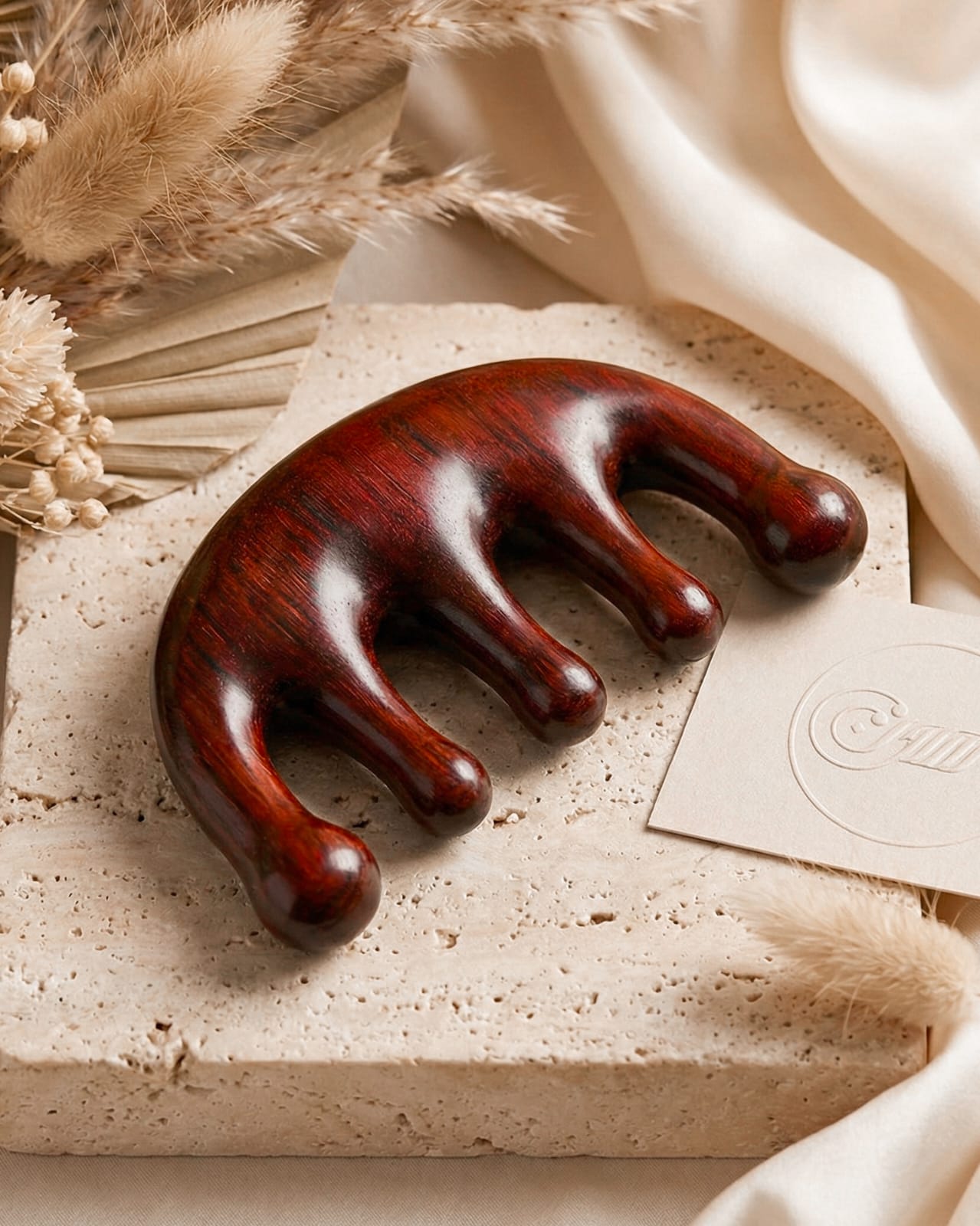Wooden back Scratcher on a textured surface with dried plants and fabric in the background